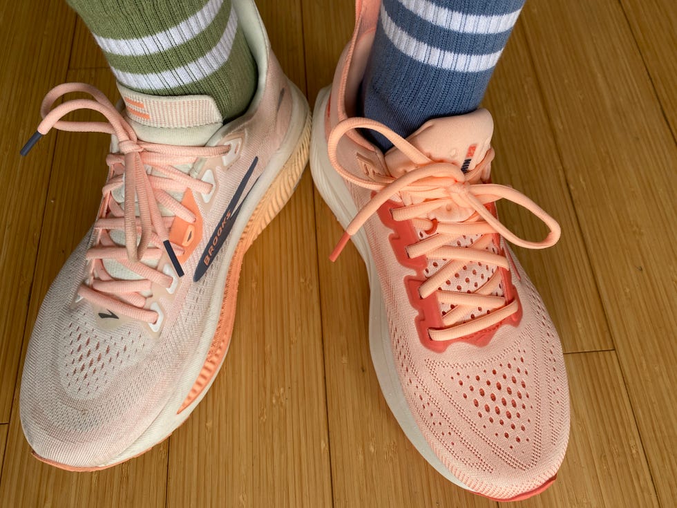 Pair of running shoes with pink accents, worn with striped socks in green and blue, on a wooden floor. Pair of running shoes with pink accents, worn with striped socks in green and blue, on a wooden floor.