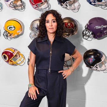 Display of American football helmets with a person posing in front.
