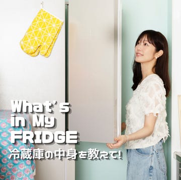 person opening fridge in a kitchen with hanging baskets and colorful pots.