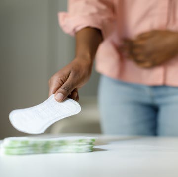 ‘i'm a gynaecologist – these are 5 warning signs your bleeding isn't normal’: woman picking up sanitary pad from table