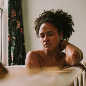 Dreamy scene of a beautiful woman in a roll top bath - she closes her eyes as she relaxes a beautiful woman closes her eyes as she relaxes in a roll top bathtub the scene is calm and still