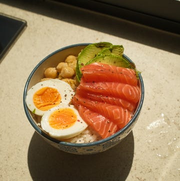 vibrant poke bowl filled with fresh salmon slices, creamy avocado, hard boiled eggs, chickpeas, and a bed of rice, creating a healthy and wholesome meal