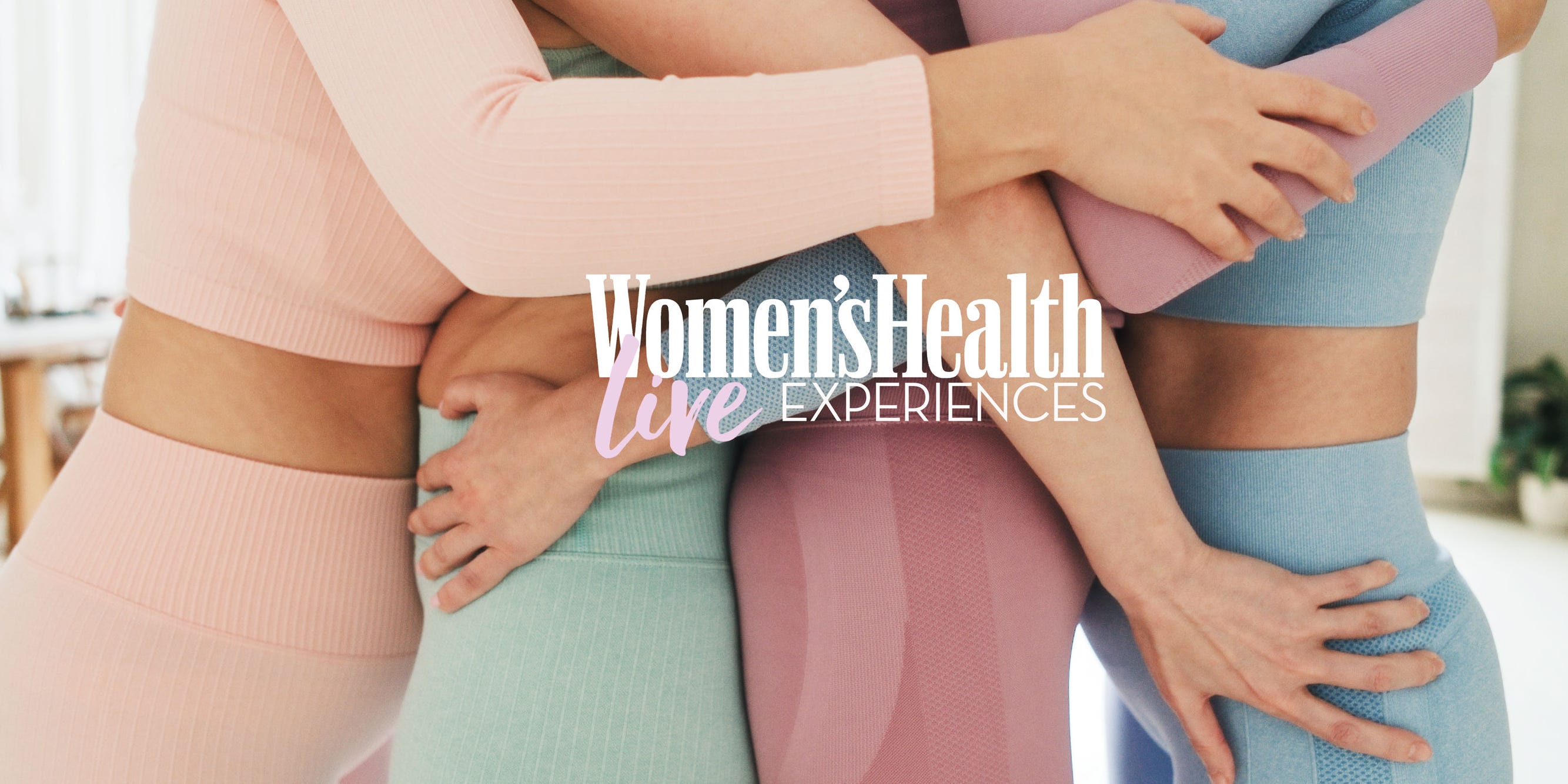Four women hugging in colorful activewear.