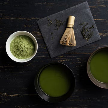 Still life of matcha tea preparation with whisk and bowls of matcha tea and tea powder, overhead view, low key Still life of matcha tea preparation with whisk and bowls of matcha tea and tea powder, overhead view, low key