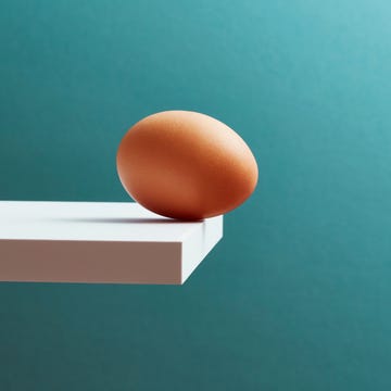 An egg teetering on the edge of a plank An egg teetering on the edge of a plank