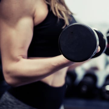 athletic woman pumping up muscles with dumbbells