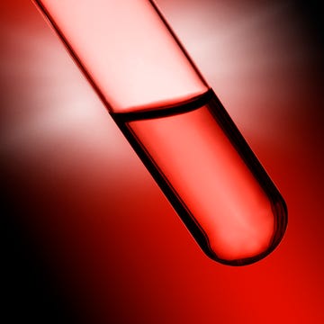 Red liquid in a transparent test tube against a dark background.