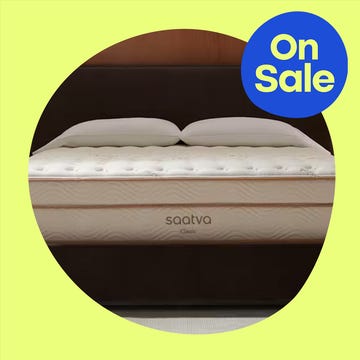 Saatva Classic mattress displayed with a sale promotion, featuring two people relaxing on the bed.