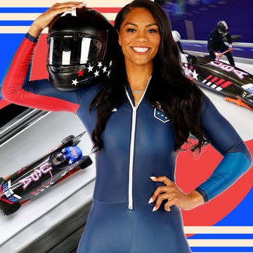 female athlete in a racing suit holding a helmet with a bobsled scene in the background