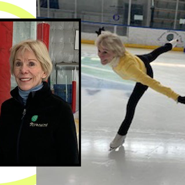 A woman in a black jacket smiles next to an ice skater performing a graceful pose on the rink in a yellow outfit.