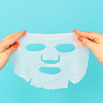 female hands with manicure hold moisturizing face mask on blue background