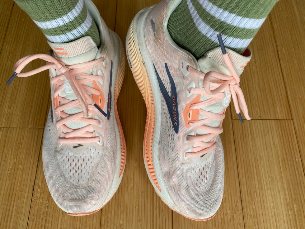 Brooks running shoes with pink accents and green striped socks on a bamboo floor. Brooks running shoes with pink accents and green striped socks on a bamboo floor.