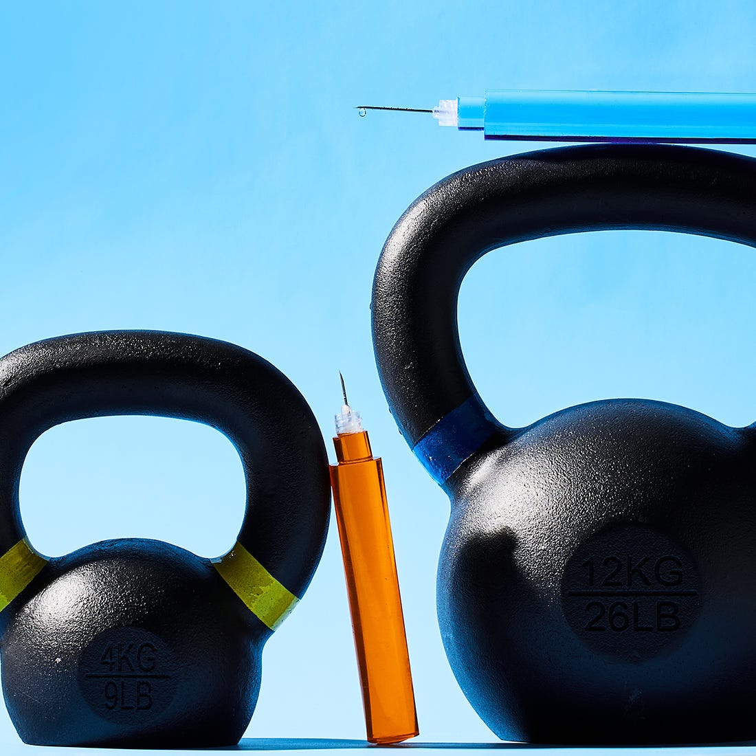 Two kettlebells in black with colored markings and syringes above them, set against a light blue background. Two kettlebells in black with colored markings and syringes above them, set against a light blue background.