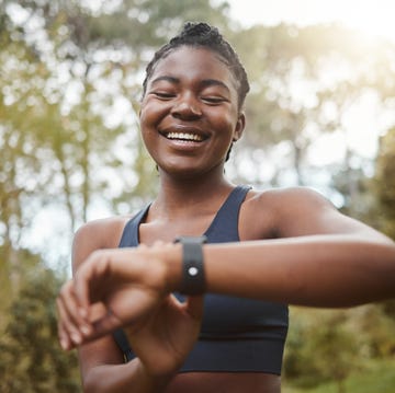 cardiologist heart health habits: woman smiling outdoors checking fitness watch