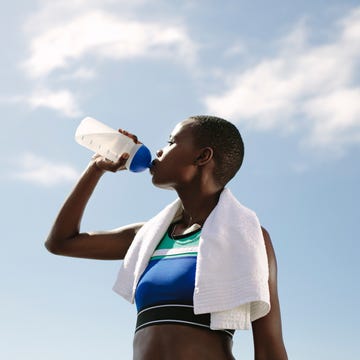 fitness woman drinking water against sky female athlete drinking water outdoors after training session