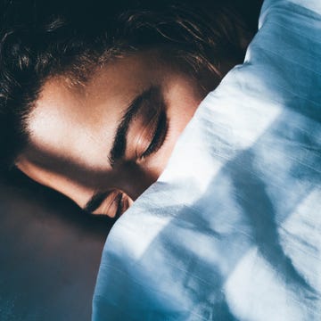 Lady sleeps in bed tossing turning in dream under blanket