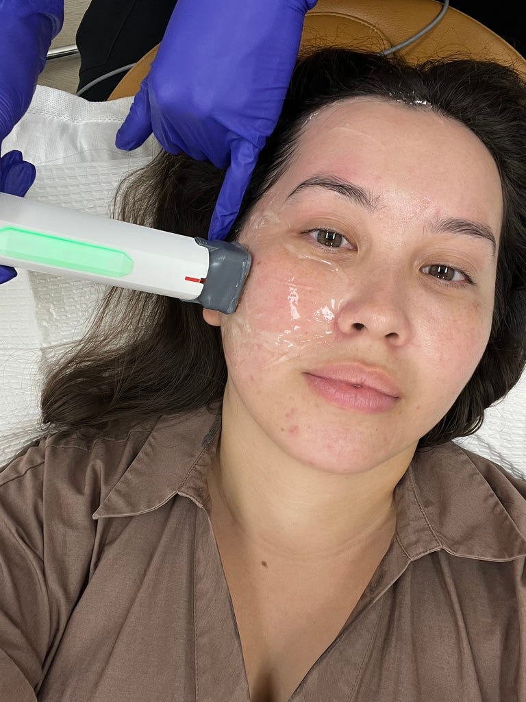 A person receiving a facial treatment with a device on their face while lying on a treatment bed.