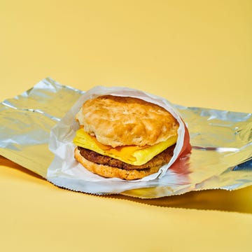 A fluffy biscuit sandwich with cheese and sausage wrapped in foil on a yellow background. A fluffy biscuit sandwich with cheese and sausage wrapped in foil on a yellow background.