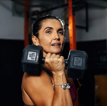 fitness determined mature woman working out at the gym. concetrate middle aged lady doing daily exercises.