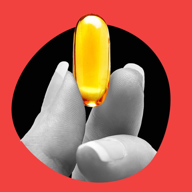 A hand holding a large yellow capsule against a contrasting background.