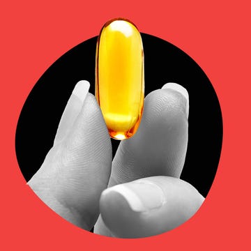 A hand holding a large yellow capsule against a contrasting background.