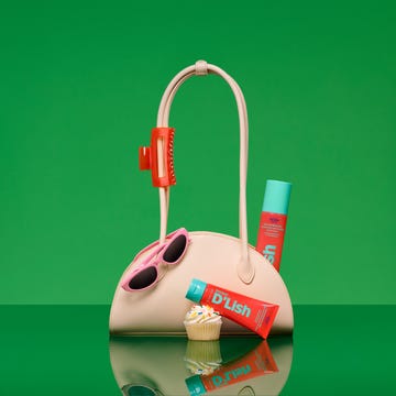 A stylish handbag with sunglasses, beauty products, and a cupcake on a reflective surface against a bright green background. A stylish handbag with sunglasses, beauty products, and a cupcake on a reflective surface against a bright green background.