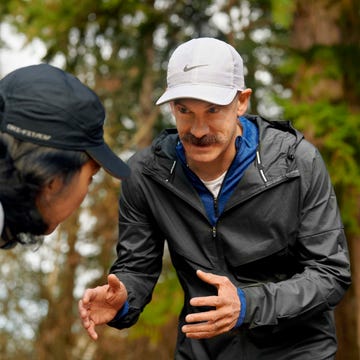 Two men engaged in a focused conversation outdoors, one demonstrating a technique in athletic gear.