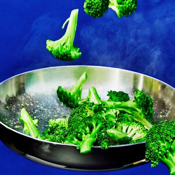 Broccoli cooking in a frying pan with steam.