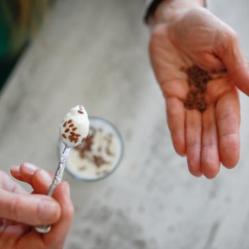 Healthy breakfast: a woman's hands sprinkle flax seeds into yogurt for healthy eating.