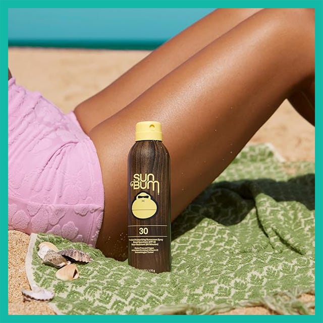 Sunscreen spray and hydrating body wash on a beach towel with seashells and a model's tanned leg in the background.