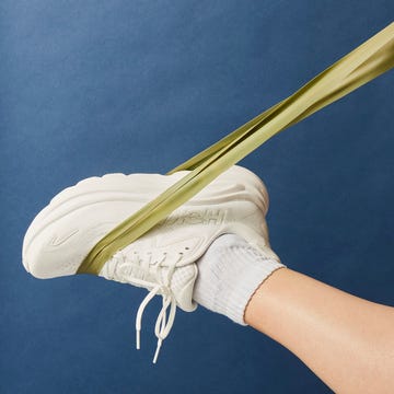 Person stretching yellow resistance band with leg. Person stretching yellow resistance band with leg.