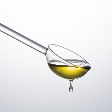 Glass spoon with yellow liquid dripping.