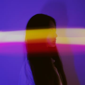 Young Asian woman surrounded by Lightbeams at night Young woman surrounded by Lightbeams at night