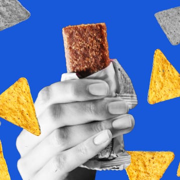 Hand holding a snack bar with tortilla chips scattered on blue background Hand holding a snack bar with tortilla chips scattered on blue background