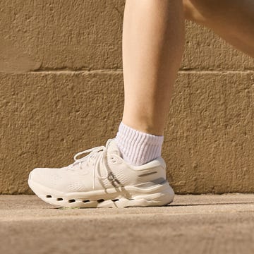 Person walking on pavement wearing white sneakers and socks.