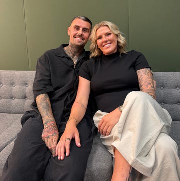 smiling couple sitting together on a couch with tattoos visible.