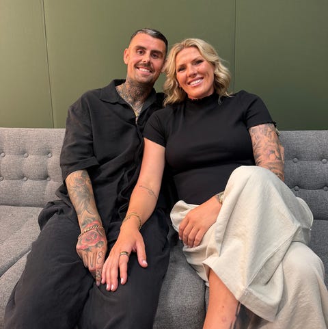 smiling couple sitting together on a couch with tattoos visible.