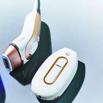 Three handheld laser hair removal devices on a reflective surface. Three handheld laser hair removal devices on a reflective surface.