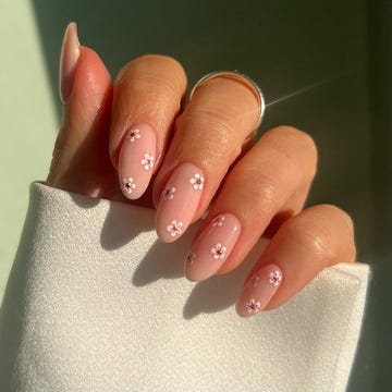 a hand with wellmanicured nails featuring pink polish and floral designs