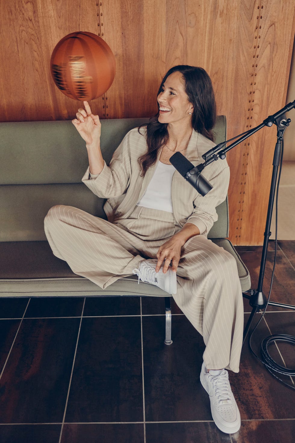 Person lounging on a couch, spinning basketball on finger, with a microphone setup nearby.