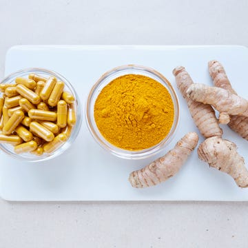 High angle view of turmeric root, powder and pills on white plate