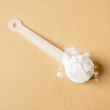 Measuring scoop with creatine powder on beige background