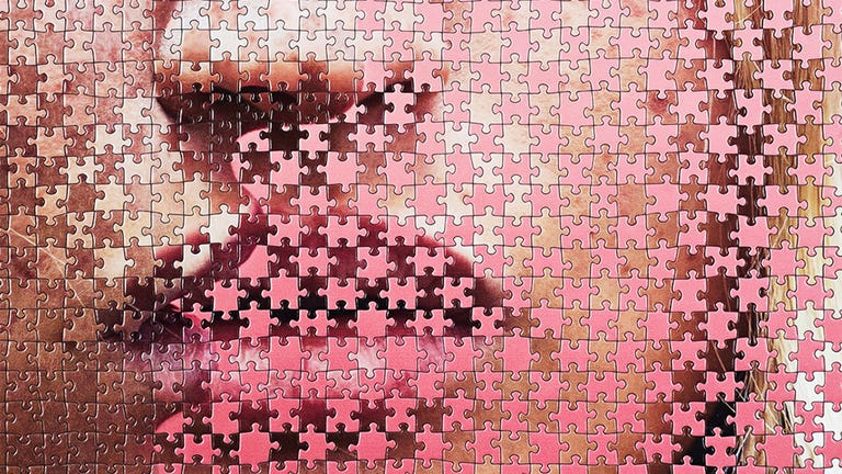 Close-up of a partially completed jigsaw puzzle featuring a stylized depiction of lips and facial features. Close-up of a partially completed jigsaw puzzle featuring a stylized depiction of lips and facial features.