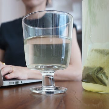 person working on a laptop with a glass of green tea.