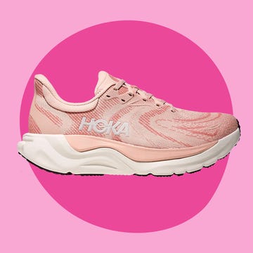 Two pairs of stylish running shoes on a pink background, one in white and gray, the other in light pink and white.