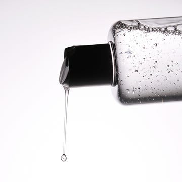 A bottle of cosmetic product with toner flowing out of it. Demonstration of the product texture. this is why you need to try Korean haircare products