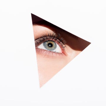woman looking out of hole close up shot of woman looking out of hole with one eye isolated on white