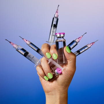 A hand holding multiple syringes and a vial against a gradient blue background. A hand holding multiple syringes and a vial against a gradient blue background.