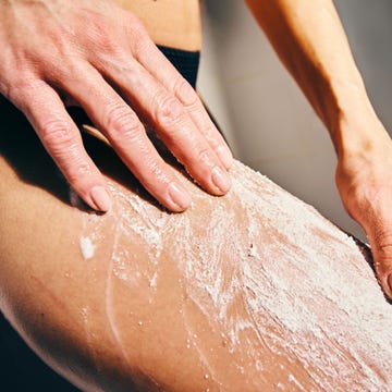 close up of hands applying lotion on skin in modern shower setting