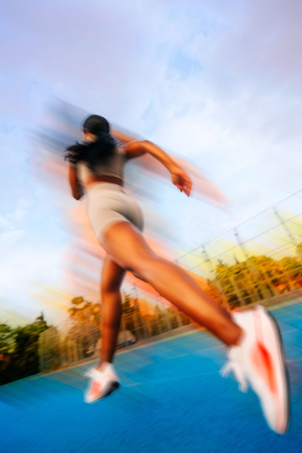 Athlete in motion running on a blue court with a blurred background and colorful lighting. Athlete in motion running on a blue court with a blurred background and colorful lighting.